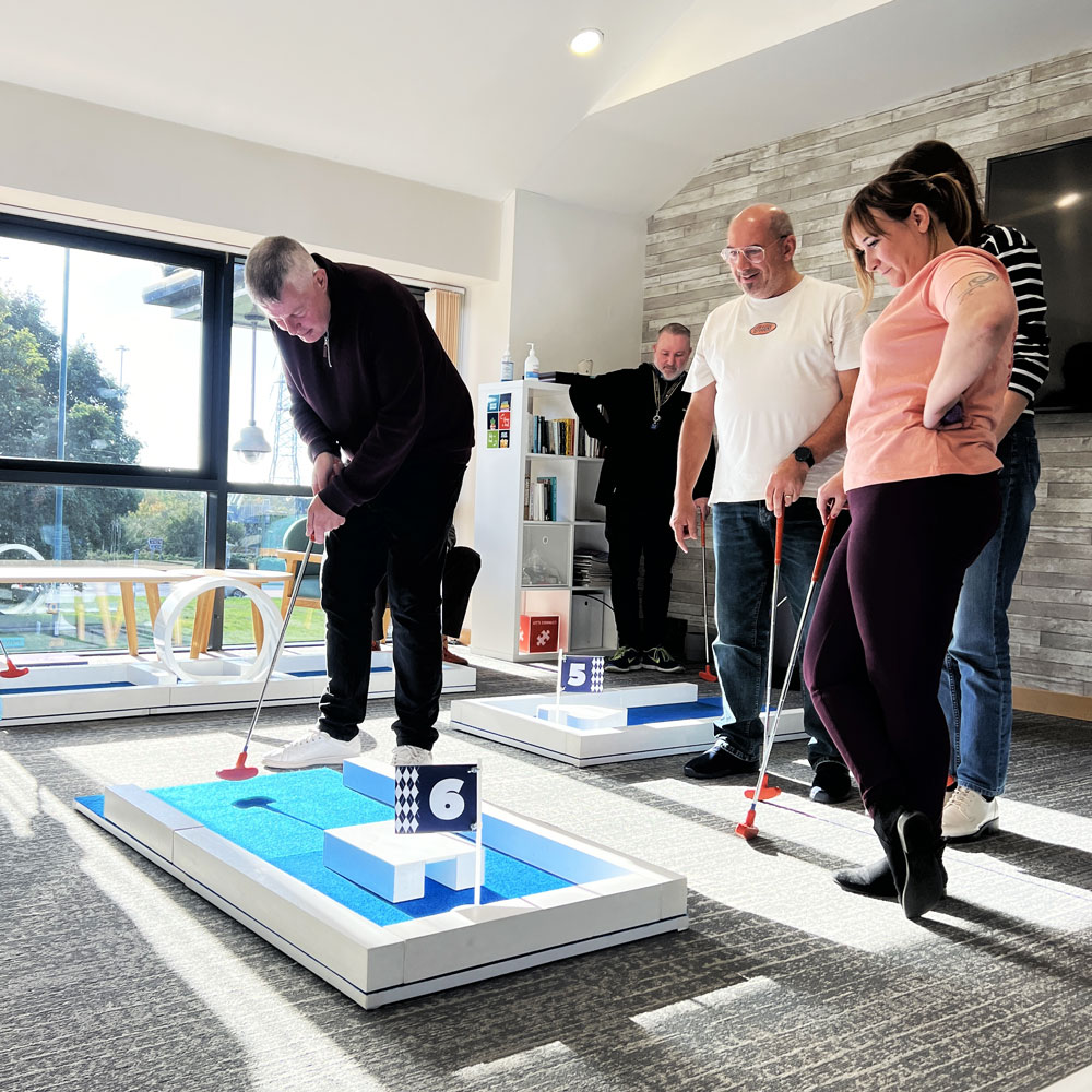 Workplace team enjoying a portable mini golf course indoors